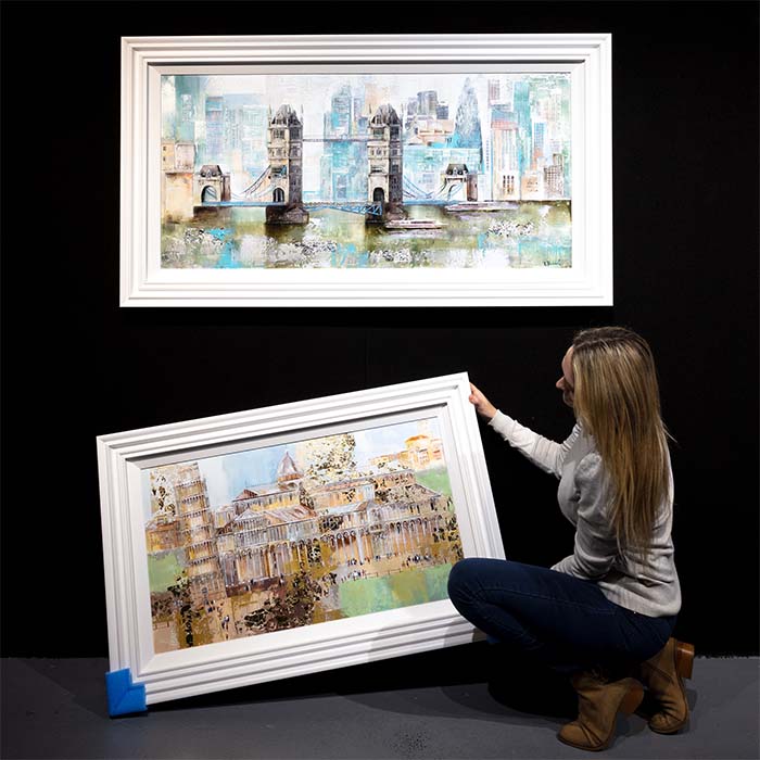 Interior photo of a Nigel Cooke Cityscape artwork in a white frame above a bed